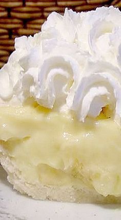 a piece of pie with whipped cream on top sits on a plate in front of a wicker basket