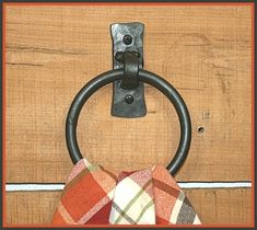 an iron ring hangs on a wooden door with plaid napkins hanging from it's handle