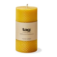 a yellow beeswax candle with the tag on it's front and bottom