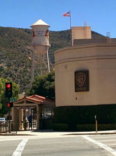 a traffic light sitting next to a building on the side of a road with a water tower in the background