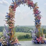 an arch made out of flowers on top of a cement slab in the middle of a field