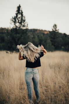 a woman with blonde hair standing in tall grass