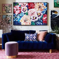 a living room filled with furniture and paintings on the wall above it's couch