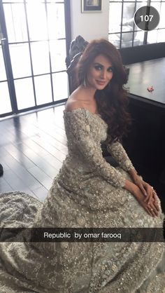 a woman sitting on top of a wooden floor wearing a dress with sequins