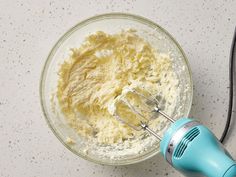 an electric mixer is mixing batter in a glass bowl