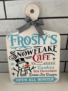 a sign hanging on the side of a brick wall that says frosty's snowflake cafe