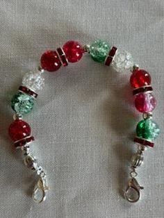 a red, green and white beaded bracelet with silver clasps on a table