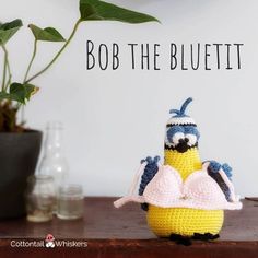 a crocheted minion sitting on top of a table next to a potted plant