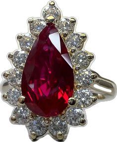 a large red stone surrounded by white and yellow diamonds in an ornate ring with gold accents