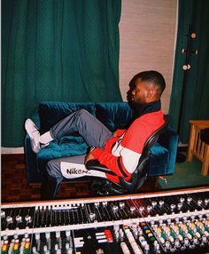 a man sitting on top of a blue couch next to sound mixing equipment