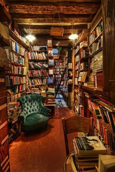 a room filled with lots of books next to a green chair and bookcases