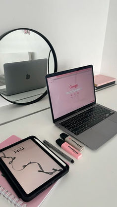 an open laptop computer sitting on top of a desk next to a notebook and pen