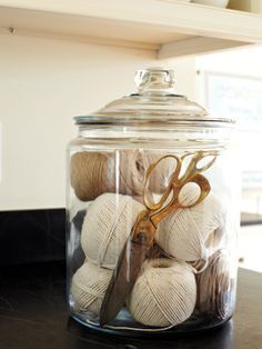 a glass jar filled with balls of yarn and scissors