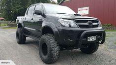 a black truck parked in front of a red barn