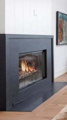 a fire place in the middle of a living room with wood floors and white walls