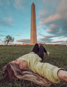 a woman laying on the ground in front of a tall obelisk at sunset