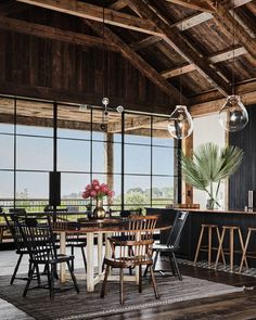 a large open kitchen and dining room area with wood flooring, black cabinetry, wooden ceiling, and glass windows