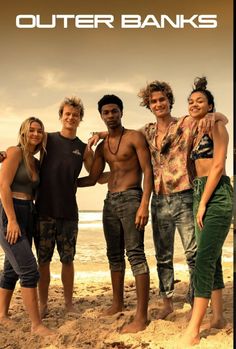 a group of people standing next to each other on top of a sand covered beach