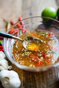 a glass bowl filled with soup next to garlic and peppers