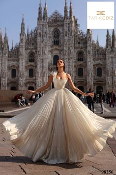 a woman in a white dress is posing for the camera with her arms spread out