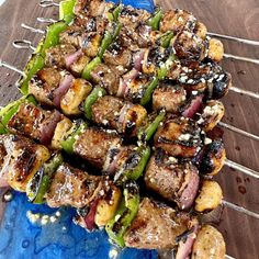 the skewers are covered with meat and vegetables on top of a blue plate