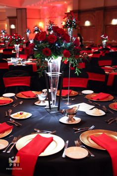 a black table cloth with red napkins and place settings is set for an event