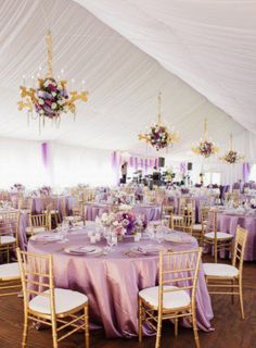 the inside of a tent with tables, chairs and chandeliers set up for an event