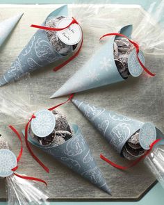 four cones are wrapped in plastic and tied with red ribbon on a wooden table top