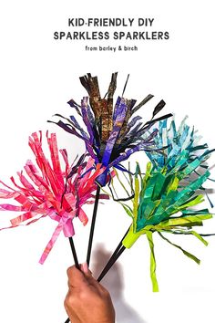 someone holding up some colorful paper flowers with the words, kid - friendly diy sparkles sparklers from barley & birch