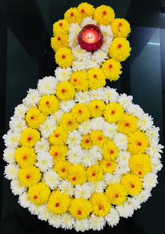 yellow and white flowers with a red candle on the top in front of a black background