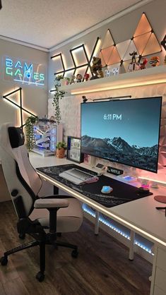 a computer desk with a large monitor and keyboard on it in front of a neon sign