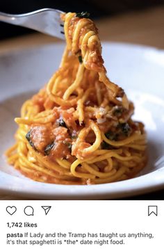 a white plate topped with spaghetti and meat covered in sauce next to a fork on top of it