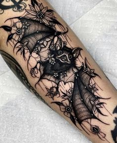 a bat with flowers on it's wings is shown in black and grey ink