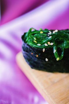 a piece of food that is sitting on a wooden cutting board with sesame seeds all over it