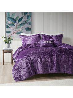 a bed with purple comforters and pillows