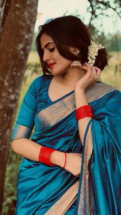 a woman in a blue sari standing next to a tree