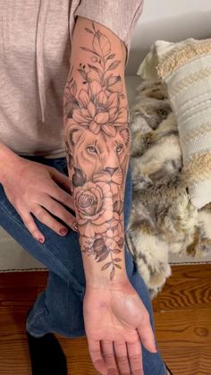 a woman is sitting on the floor with her arm covered in flowers and a lion tattoo