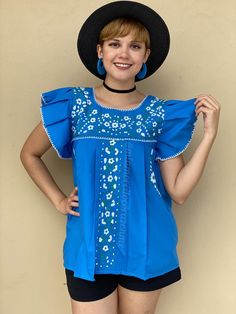 "Blue ruffled sleeve floral embroidered mexican blouse women, boho hippie modern top, mexico beach vacation, hand embroidered flowers Look unique and be the center of the party with this hand-embroidered Mexican blouse, this top will definitely eye catching. This is a traditional Mexican top with a twist; ruffled sleeve, one of Mi Amorcito Corazon exclusive designs. Blue top with gorgeous details of white and teal embroidered flowers. Top is loose fit and flowy. Fits size SMALL (Tag reads M, but Flowy Floral Embroidered Beach Tops, Flowy Floral Embroidered Tops For Beach, Flowy Cotton Blouse With Floral Embroidery, Summer Bohemian Blouse With Ruffles, Flowy Vacation Tops With Floral Embroidery, Summer Embroidered Blouse With Flutter Sleeves, Bohemian Short Sleeve Peasant Top With Ruffles, Bohemian Ruffled Summer Blouse, Bohemian Flowy Embroidered Summer Top