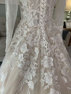 the back of a wedding dress with white flowers on it, and sheer lace overlays