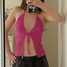 a woman taking a selfie in front of a mirror wearing a pink crochet top