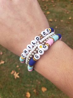 a person's arm with bracelets and beads on it that say child of god