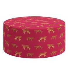 a pink and gold patterned round ottoman with giraffes on the top, sitting in front of a white background