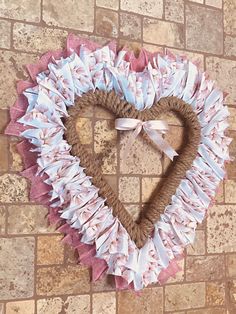 a heart shaped wreath made out of ruffles on a brick wall with a bow