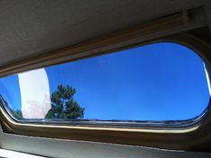 the view from inside a vehicle looking at trees and blue sky in the rear window