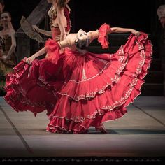 two women in red dresses are dancing on stage