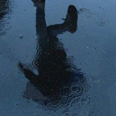 a person standing in the middle of a puddle with an umbrella over their head and feet