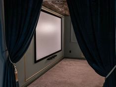 a large screen in the corner of a room with curtains on both sides and a curtained window