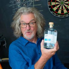 a man holding a bottle of water in front of a dart board