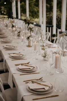 the table is set with white linens and place settings