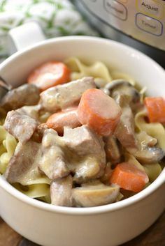 a white bowl filled with pasta and meat next to an instant pressure cooker in the background